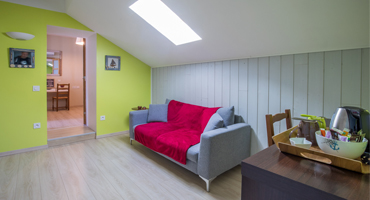Une des trois chambres d'hôtes de charme à Virson (17) proche Rochefort : salon privatif avec canapé, pan de mur vert, une décoration de chambre en hommage à l'Île d'Aix.